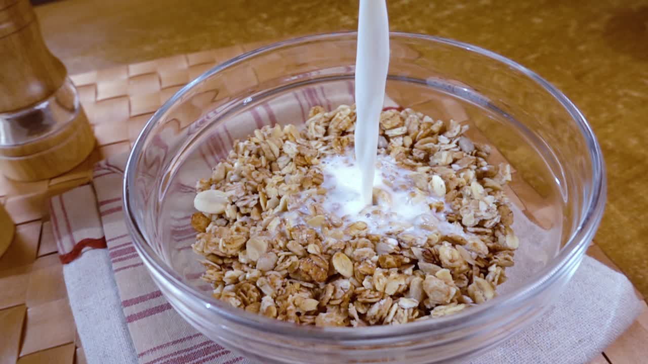 muesli de cereales de grano entero en un tazón para un delicioso desayuno matutino con leche. cámara lenta con toma de seguimiento de rotación.