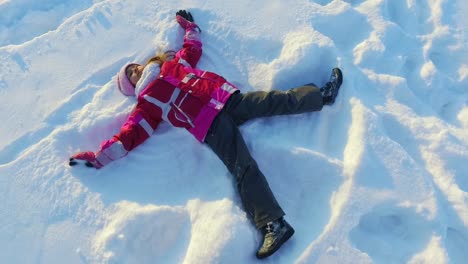 Draufsicht-Kleines-Mädchen-Macht-Schneeengel.-Winterkind.-Sonniger-Wintertag