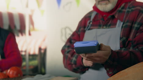 farmer using a payment terminal man contactless pays for purchases to farmer using smartphone autumn fair outdoors vegetarian and organic food agriculture point of sale system
