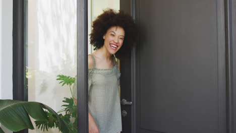 mixed race woman opening a entrance door and looking at camera