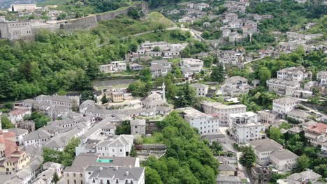 Drone-view-in-Albania-flying-in-Gjirokaster-town-over-a-medieval-castle-on-high-ground-fort-showing-the-brick-brown-roof-houses