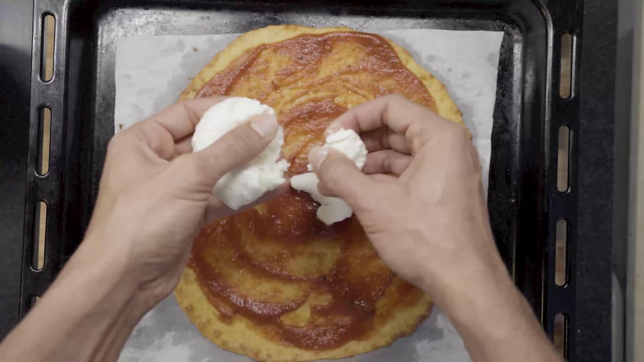 hacer pizza casera, poner queso mozzarella en la base de masa de pizza