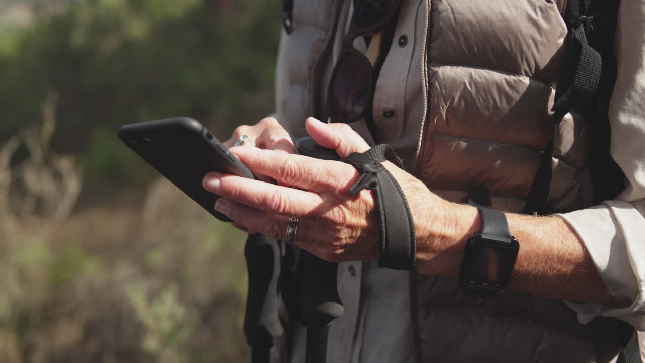 vista de cerca de una mujer mayor con un teléfono inteligente en el bosque
