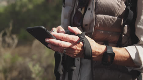 close up view of senior woman holding smartphone in forest