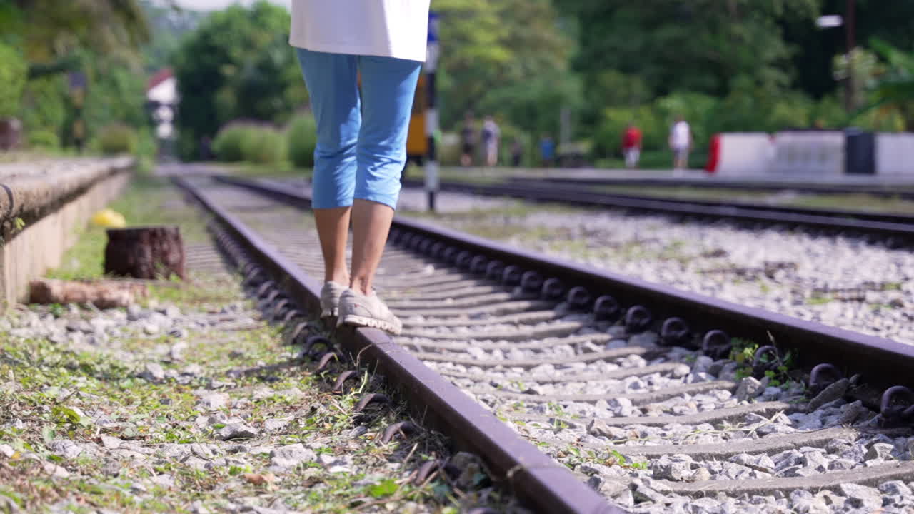 Woman balancing herself at the train track in slow motion
