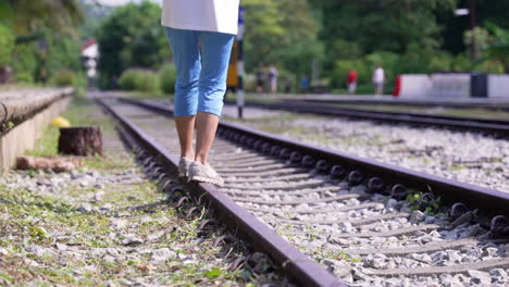 woman balancing herself at the train track in slow motion