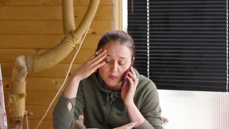 젊은 여성이 전화로 이야기하고 얼굴을 만지며 걱정하고, 위로 기울입니다.