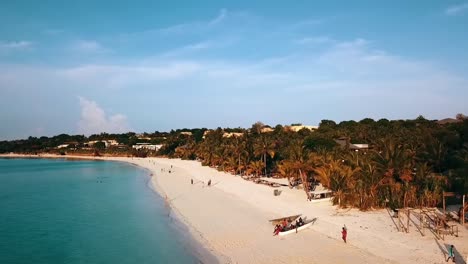 buttery soft aerial flight fly forwards drone shot over coast line at sun set over people with long shadow