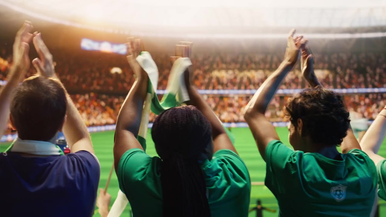Primer plano de aficionados al fútbol aplaudiendo en un estadio abarrotado durante el día del partido