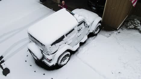 a man brushes off his vehicle after heavy overnight snow