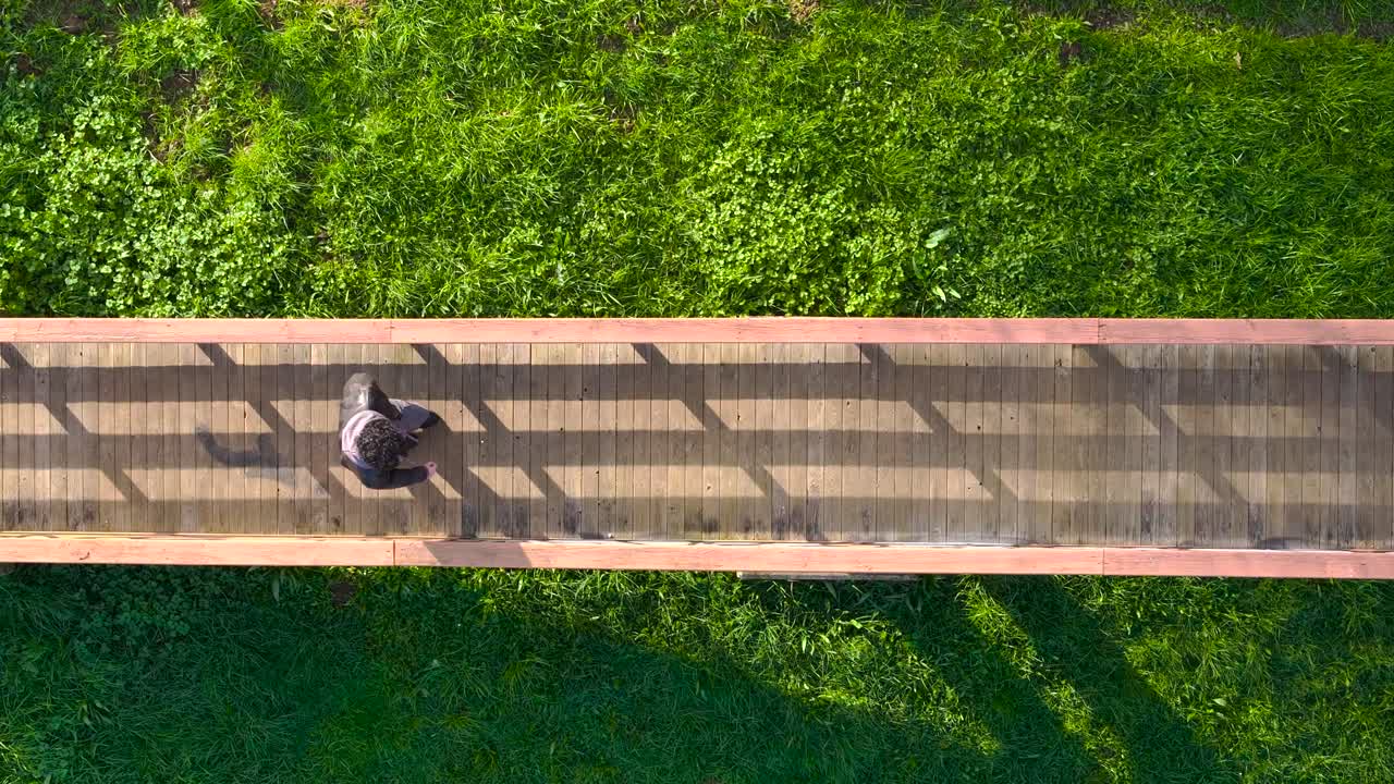 초록색 잔디 위 에 있는 나무 다리 를 가로질러 고 있는 사람 의 위상
