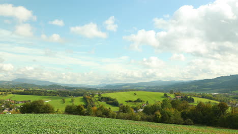 Moving-clouds-and-their-shadows-reflect-on-the-ground-above-the-landscape-and-field-in-the-Beskid-National-Park-area,-background-of-high-hills-during-a-sunny-day-captured-in-4k-60fps