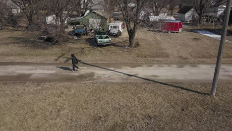 Un-Dron-Aéreo-Disparó-Siguiendo-A-Un-Joven-Adolescente-De-Secundaria-Que-Llevaba-Una-Mochila-Caminando-Por-Una-Carretera-Durante-El-Invierno-En-Un-Día-Frío