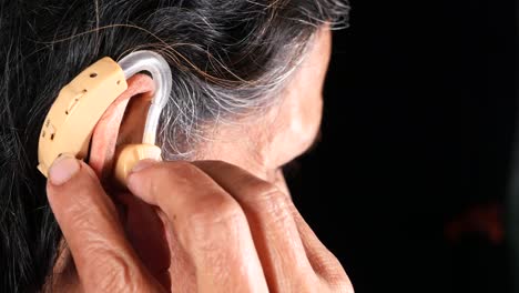 elderly woman adjusting her hearing aid