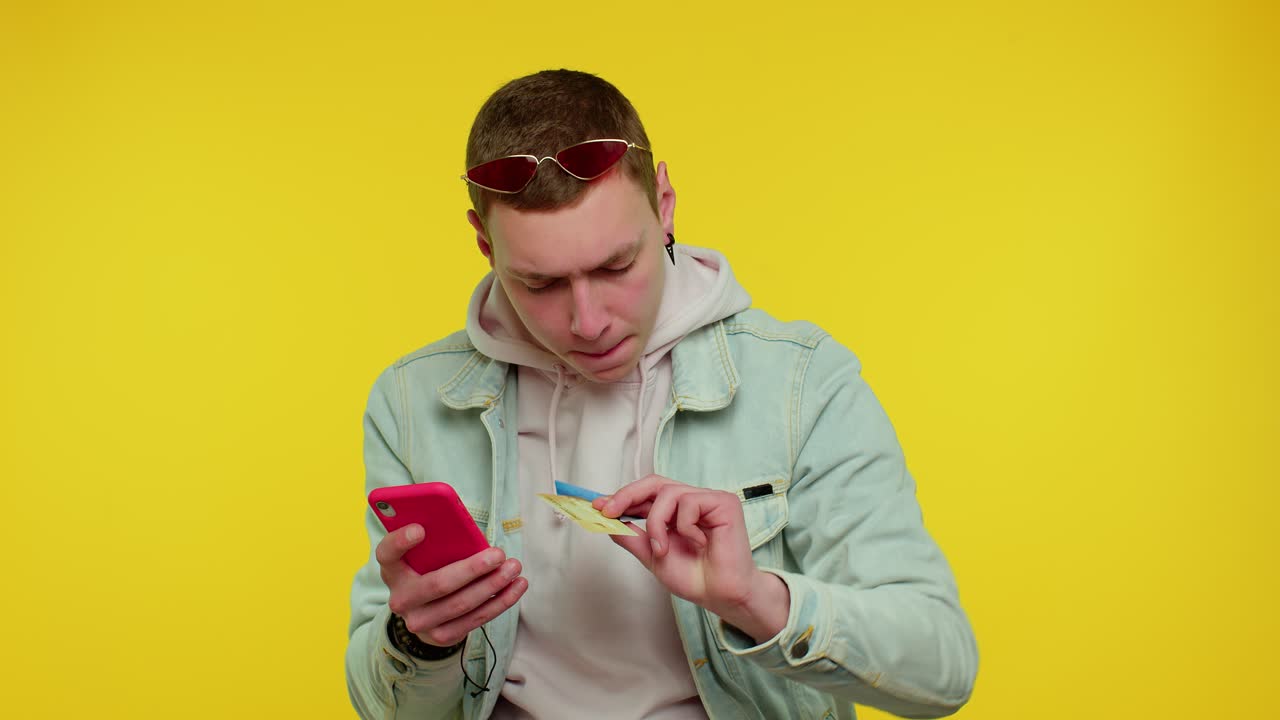 Teen man using credit bank cards and smartphone while transferring money, purchases online shopping