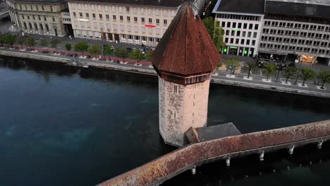 Vista-Aérea-Del-Puente-Kapellbrücke-En-Lucerna,-Suiza-Girando-Alrededor-De-La-Torre-Del-Puente-Para-Revelar-El-Histórico-Altstadt