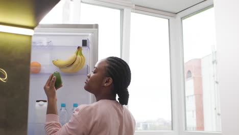 woman taking an avocado from the fridge