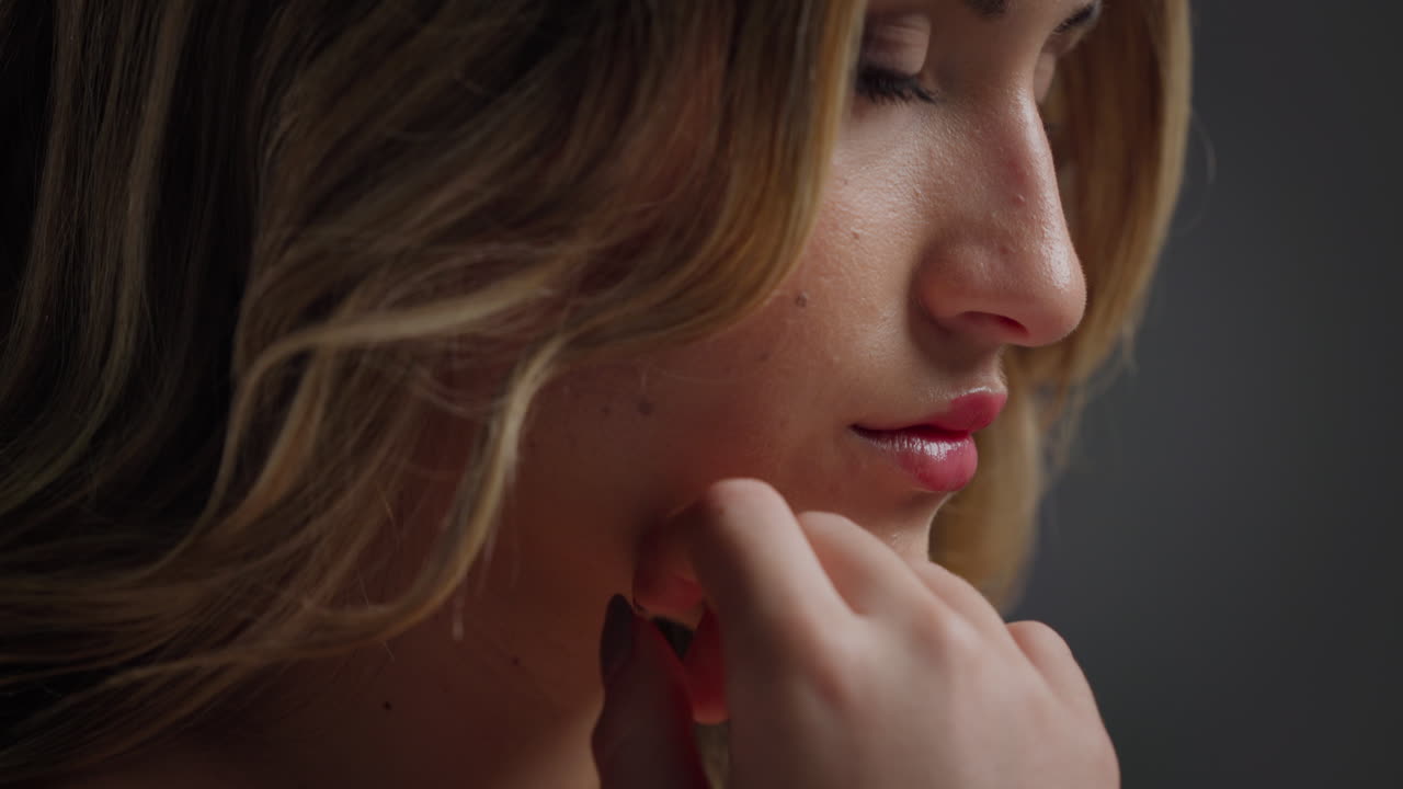 Close-up of a woman's face with blonde hair and manicured nails