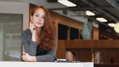 portrait of casually dressed young businesswoman standing in modern open plan workplace