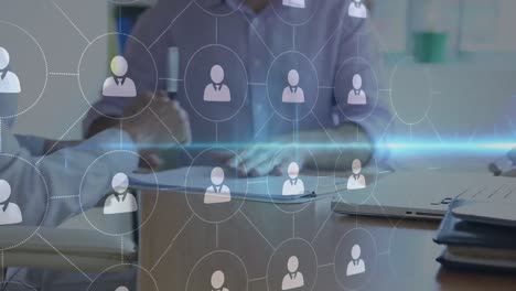 businessmen signing documents and shaking hands with connected people icons in the foreground