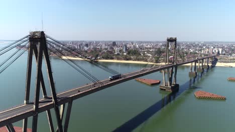 Vista-Aérea-Del-Tráfico-En-El-Puente-Que-Conecta-La-Resistencia-Con-Corrientes,-Con-La-Ciudad-De-Corrientes-Al-Fondo.