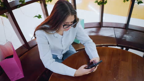 overhead view of young woman chatting with business associate over phone with hand placed on a round table in a modern, decorated workspace, demonstrating remote communication