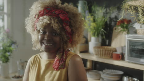portrait of cheerful african american woman in kitchen