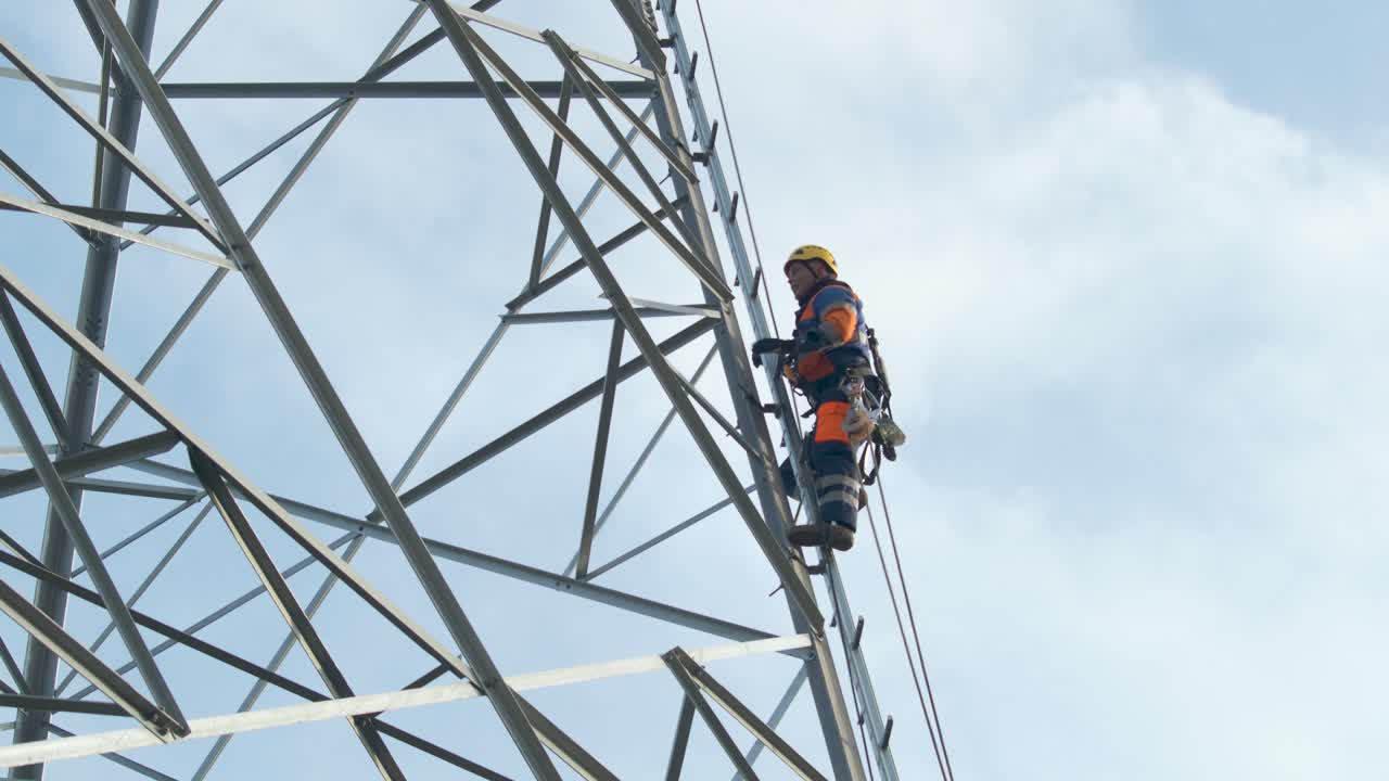 Electrician climbs up pylon, secured with a rope