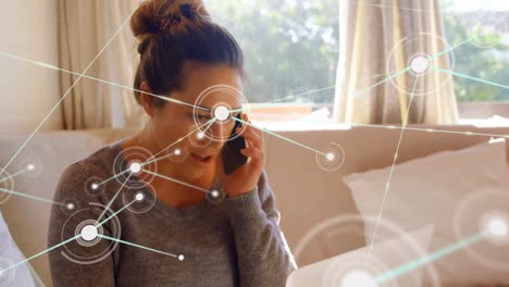Animation-of-network-of-connections-over-caucasian-woman-talking-on-smartphone-at-home