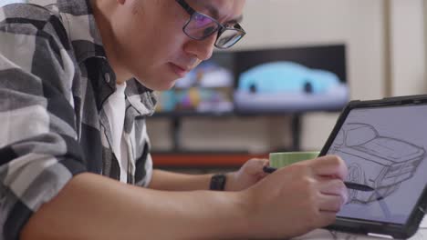 close up of asian male drinking coffee while drawing new car design concept on a tablet in the studio with tv and computers display 3d electric car model