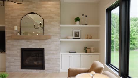 panning shot of white living room shelves by a sunlit window, adorned with plants, photos, and pottery next to a cozy fireplace