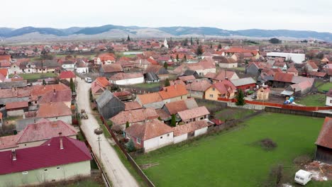 aerial view of transylvanian village in sansimion, harghita county, romania with distant view of ciuc mountains in background