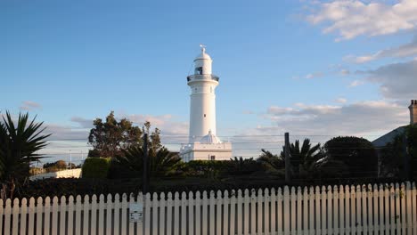 tracking shot of white lighthouse and blue sky at sunset