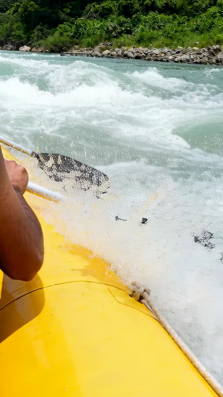 Video verticale: Rafter di acque bianche che si avvicina con giubbotto di salvataggio blu, usando una pagaia doppia per guidare il gommone