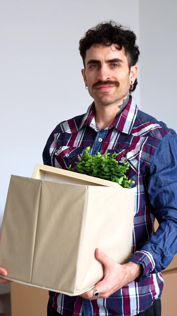 Joven sosteniendo una caja de cartón mientras se muda a un nuevo hogar