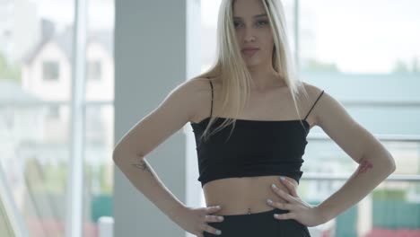 fit girl in black clothes performing contemporary. female dancer shows flowing motions, body and hands waves at white room. modern ballet dance choreography. young woman is moving smoothly