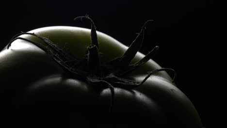 green tomato in rotation on black background.