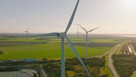 aerial slow motion shot of wind turbines and a road in a rural area of the netherlands around sunset on a beautiful sunny day