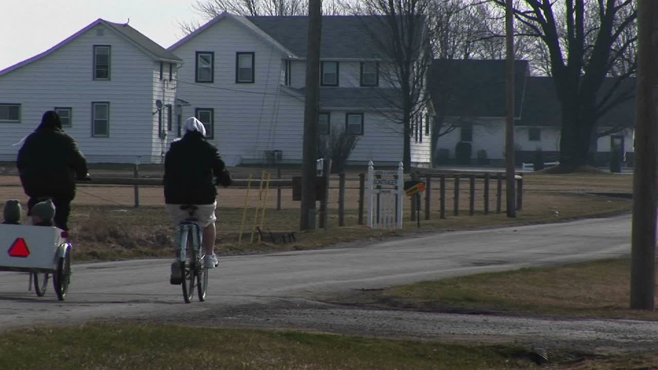 자전거를 탄 젊은이들이 차일드 캐리어에 아주 어린 두 아이를 태우고 있습니다.