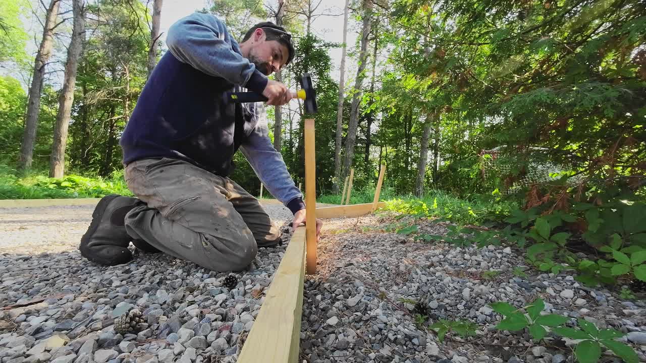 Closeup Shot Of A Carpenter Hitting Wooden Staked Into The Ground, Outdoor Formwork Construction Project.