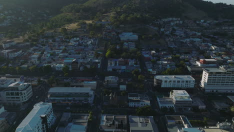 Adelante-Vuelan-Por-Encima-Del-Barrio-Urbano.-Hileras-De-Casas-Residenciales-En-Pendiente-En-Las-Afueras-De-La-Ciudad.-Carretera-Principal-Muy-Transitada.-Ciudad-Del-Cabo,-Sudáfrica