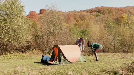 beautiful young couple helping each other setting up the camping tent