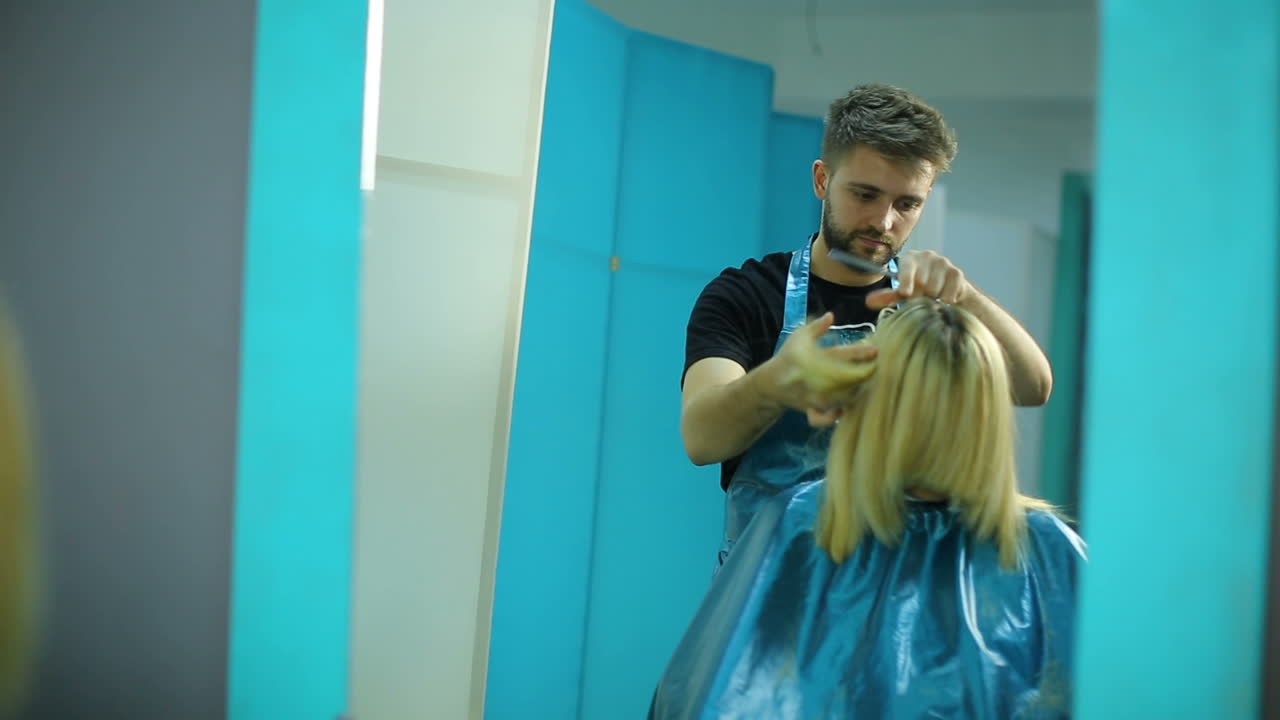 Stylist knipt het haar van een vrouw in de salon.