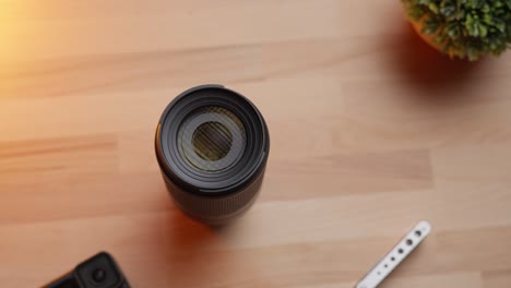 camera lens and action camera on a wooden desk lit by warm sunlight
