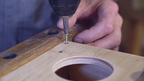 Man boring holes using steel drill indoors