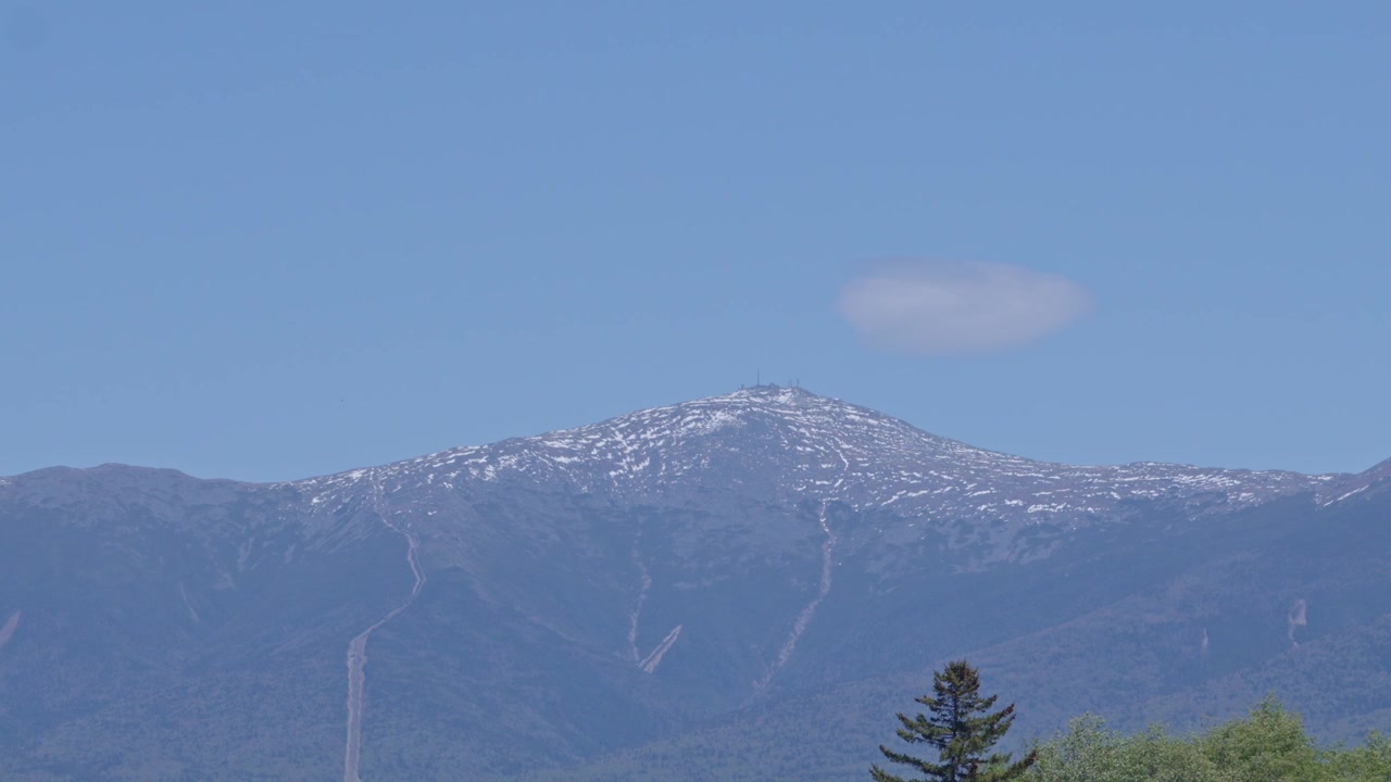 Vista del lontano Monte Washington con chiazze di neve e una singola nuvola nella Foresta Nazionale di White Mountain, Stati Uniti. Inquadratura statica, spazio per il testo.