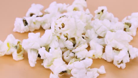 close up view of popcorn rotating on orange surface, 4k macro shot