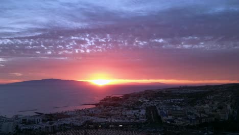 A-breathtaking-sunset-over-the-coast-of-Tenerife,-Spain,-reveals-the-beauty-of-two-distant-Canary-Islands-and-the-mesmerizing-reflection-of-sunlight-in-the-clouds