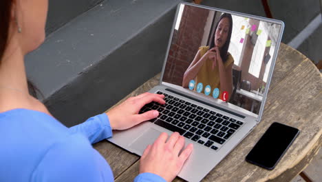 sección media de una mujer caucásica haciendo una videollamada con una colega en una computadora portátil