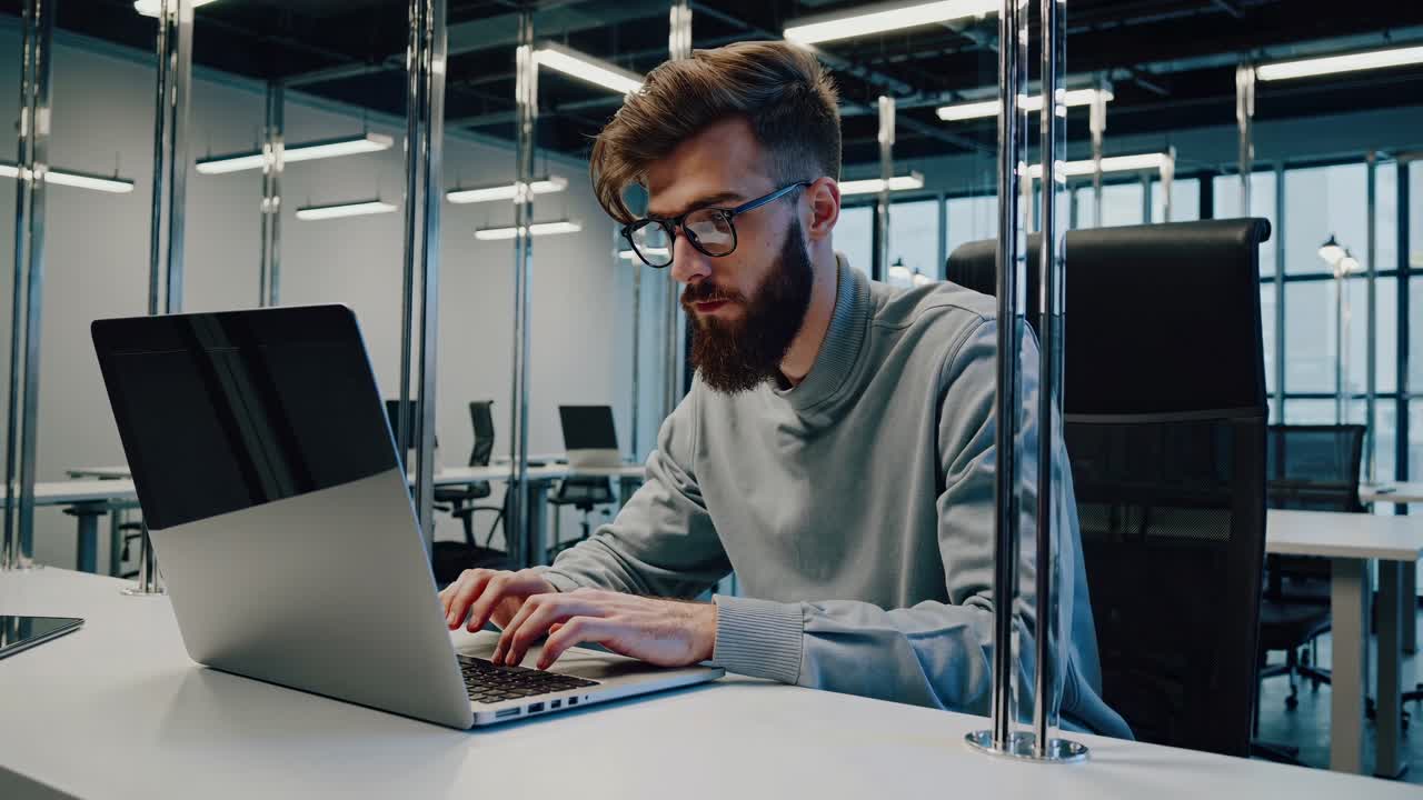 Professional businessman working at modern office desk, typing on laptop with concentration while using digital technology for business communication and productivity
